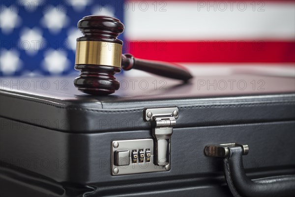 Leather briefcase and gavel resting on table with american flag behind