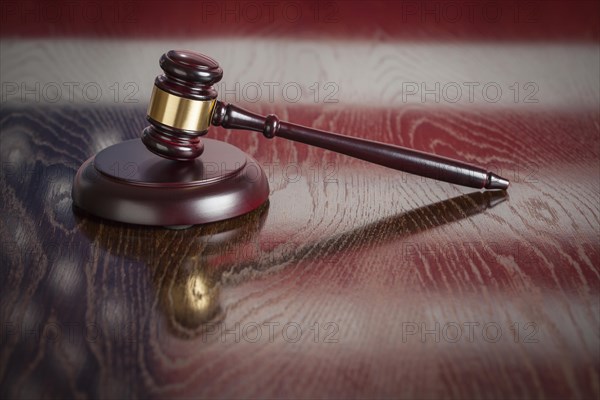 Wooden gavel resting on american flag reflecting table