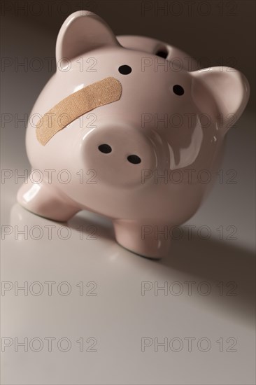 Piggy bank with bandage on face on gradated background