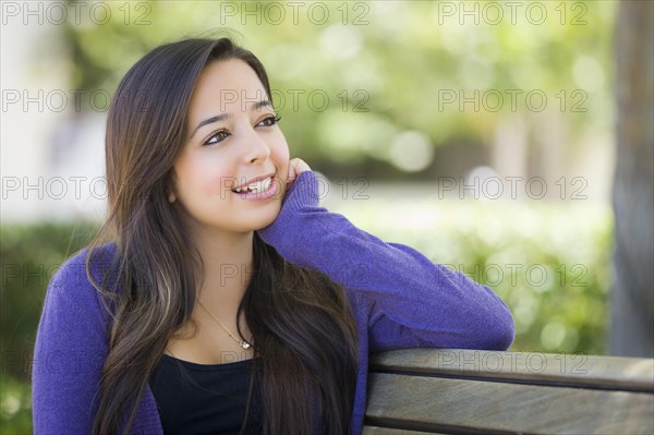 Happy mixed-race female student portrait on school campus bench