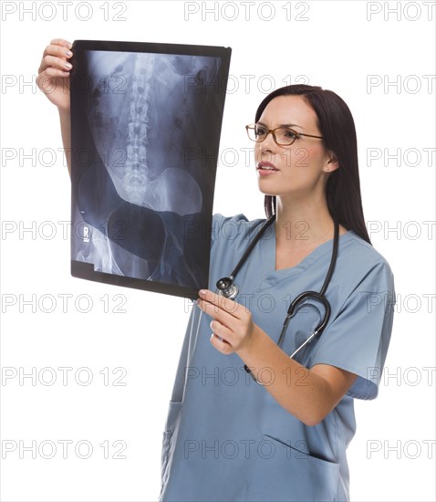 Attractive mixed-race female nurse or doctor wearing scrubs and stethoscope reviewing an x-ray isolated on a white background