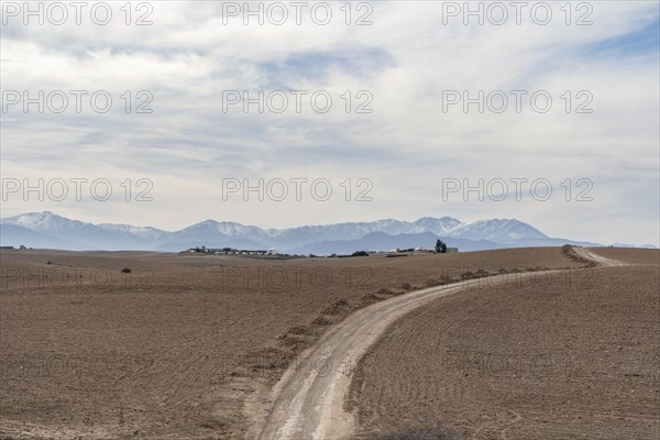 Dirt road through Agafay desert leading to Atlas Mountains