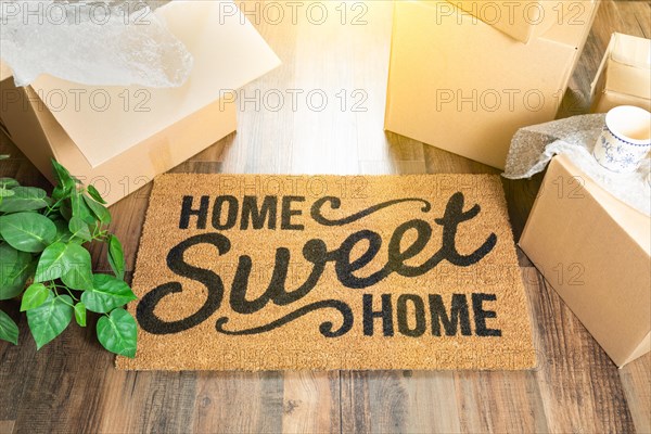 Home sweet home welcome mat and moving boxes on hard wood floor