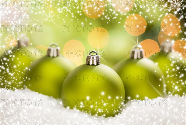 Beautiful matt green christmas ornaments on snow flakes over an abstract snow and light background with room for your own text