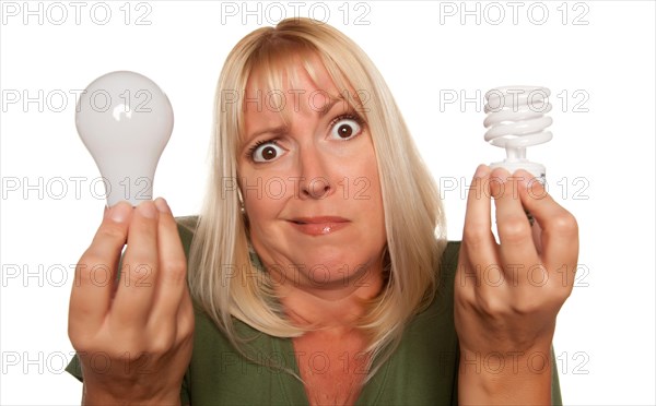 Funny faced woman holds energy saving and regular light bulbs isolated on a white background