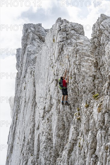 Young man climbing a vertical rock face without a rope