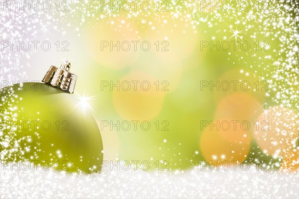 Beautiful matt green christmas ornament on snow flakes over an abstract snow and light background with room for your own text