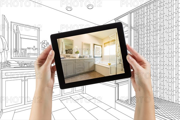 Hands holding computer tablet with master bathroom photo on screen and drawing behind