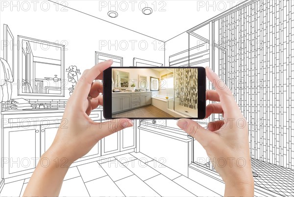 Hands holding smart phone with master bathroom photo on screen and drawing behind