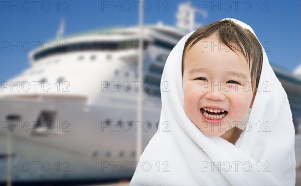 Happy mixed-race chinese and caucasian boy near cruise ship wrapped in A towel