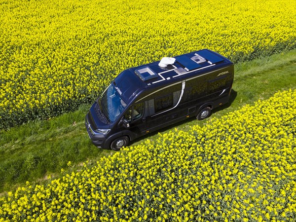 Drone shot of a camper van in a rape field