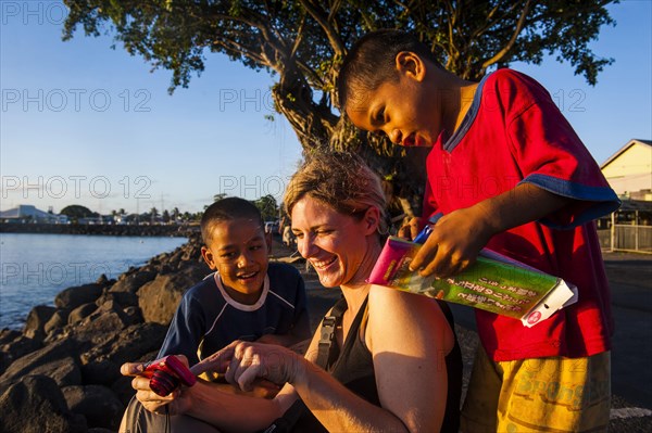 Western woman showing photos on a digi cam to local boys