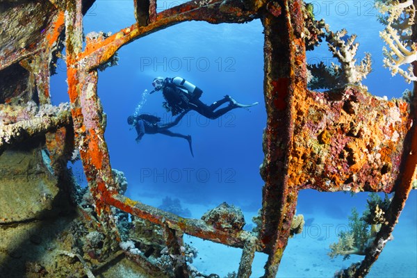 Two divers looking at shipwreck sailing ship