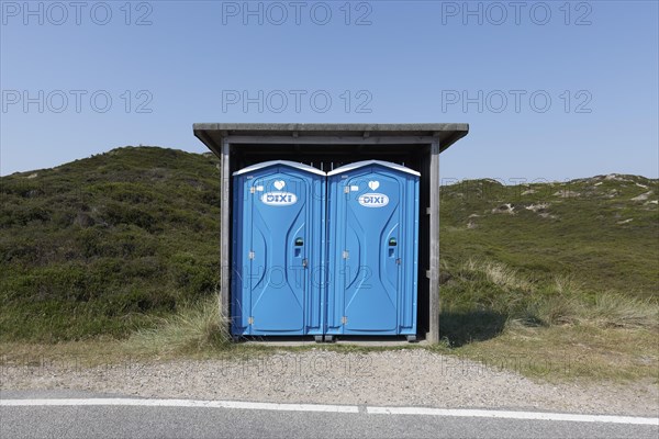 Two blue DIXI toilet stalls on a road
