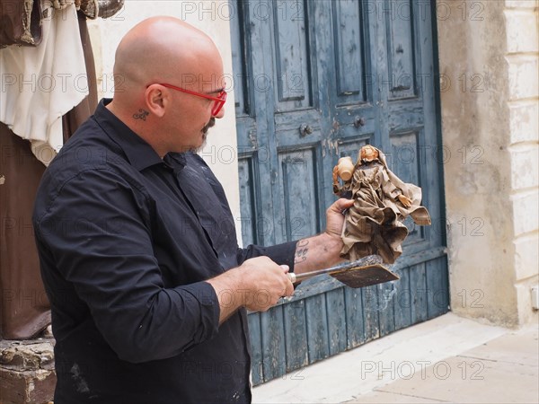 Artist creates a statue of a saint in the traditional way
