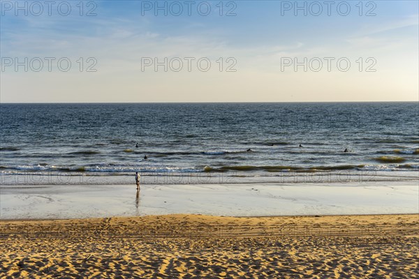 Surfers training skills in the ocean with their coach on the beach