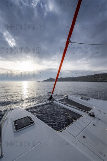 Recessed headsail and deck with net of a sailing catamaran in evening light
