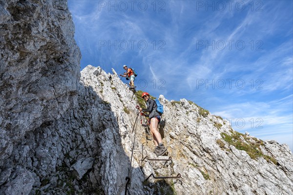 Mountaineers climbing a ladder on a secured via ferrata
