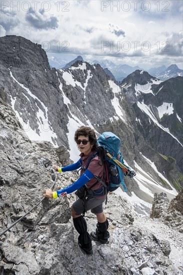 Mountaineer on a secured ridge trail with remnants of snow