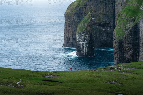 A person standing in the distance in front of Asmundarstakkur cliff