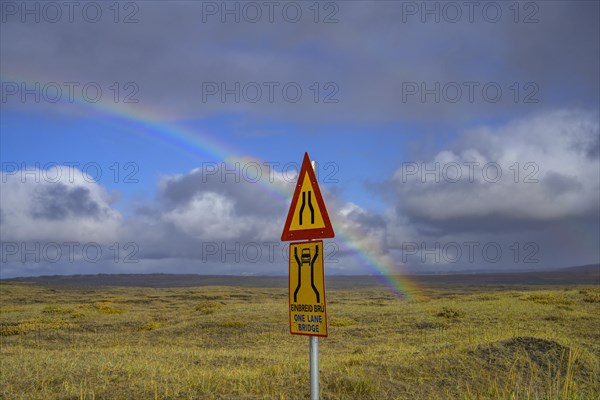 Rainbow over the autumn coloured landscape and road sign one lane bridge