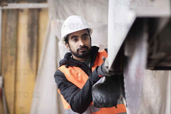 Technician with beard and helmet works in a workshop
