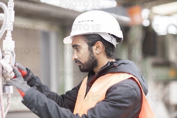 Technician with beard and helmet works in a workshop