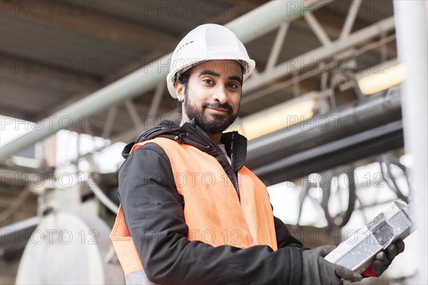Technician with beard and helmet works in a workshop