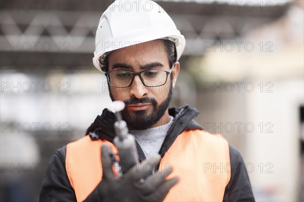 Technician with beard and helmet works in a workshop