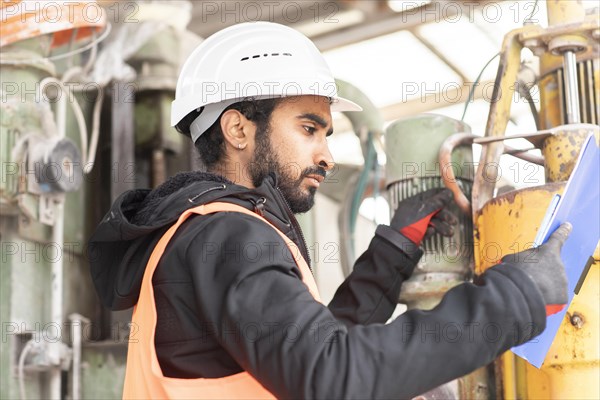 Technician with beard and helmet works in a workshop