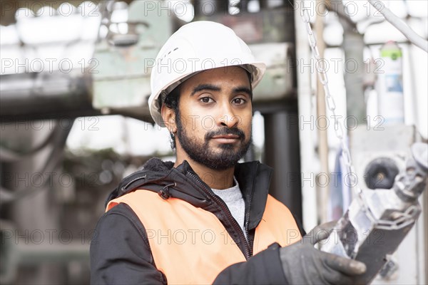 Technician with beard and helmet works in a workshop