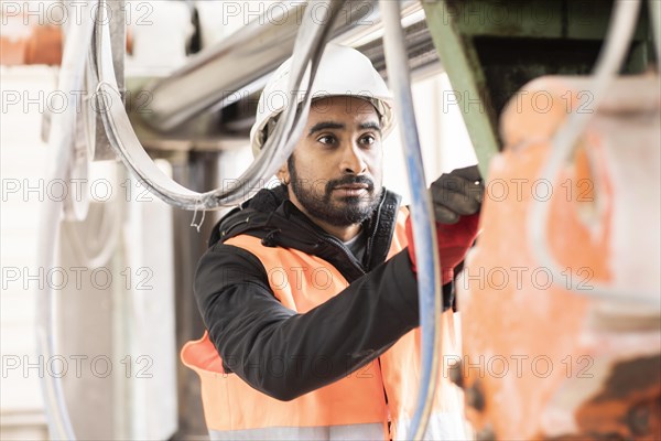 Technician with beard and helmet works in a workshop