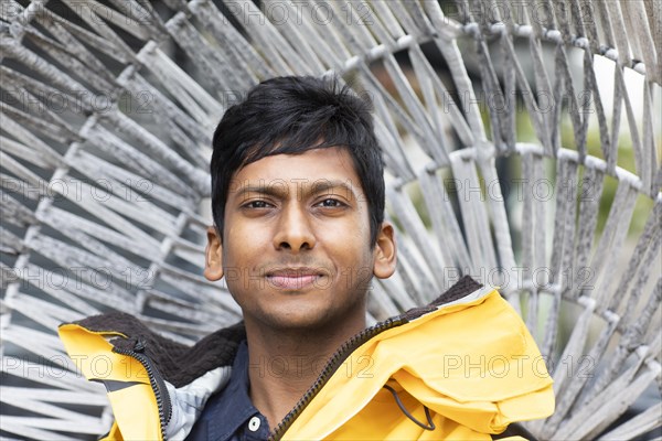 Young man with yellow jacket in front of a wicker chair
