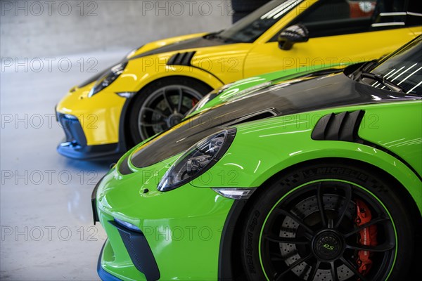 Side view of front with round headlights and rim of Porsche 911 GT3 RS race car in pitbox