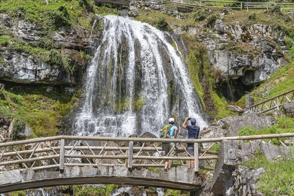 Hikers at the waterfall in front of the Saint Beatus Caves