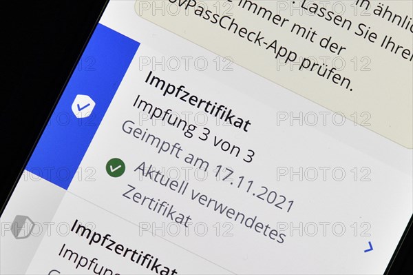 Symbolic photo App CovPass on smartphone with digital European vaccination certificate after third booster vaccination against Covid-19