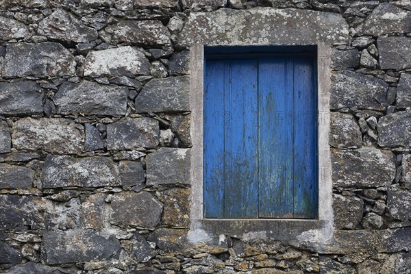 Residential house with stone facade and blue closed window in Rocha da Relva