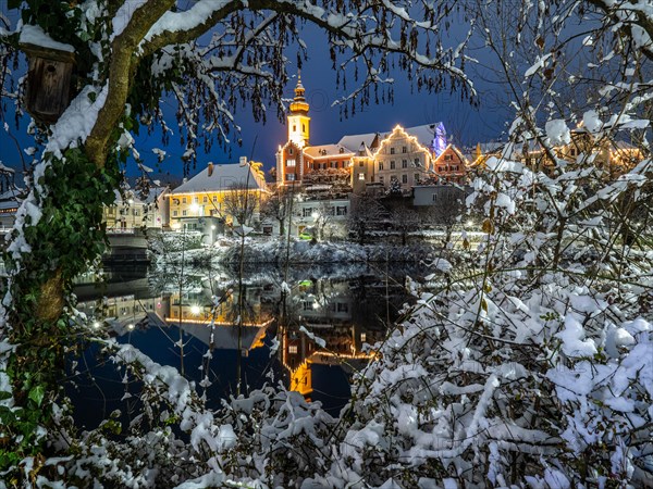 Christmas illuminated house facade of Frohnleiten reflected in the river Mur