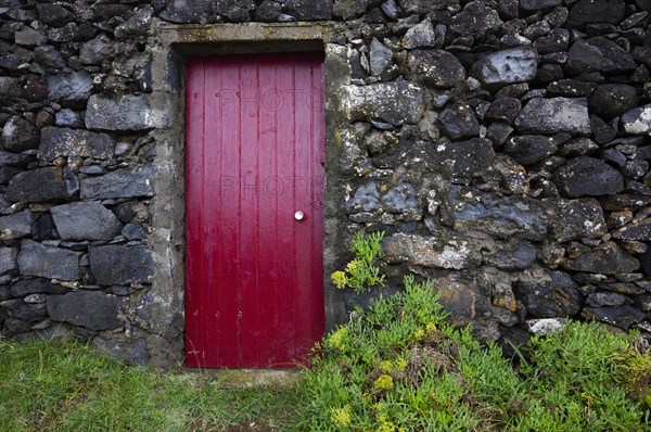 Lava stone house facade with red front door