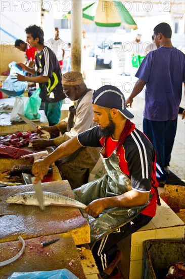 Men descale the fish for cash and process them into practical units with large cleavers