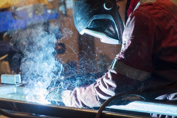 Factory worker welding in a manufacturing plant