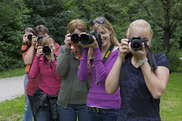 Six photographing woman on a green meadow