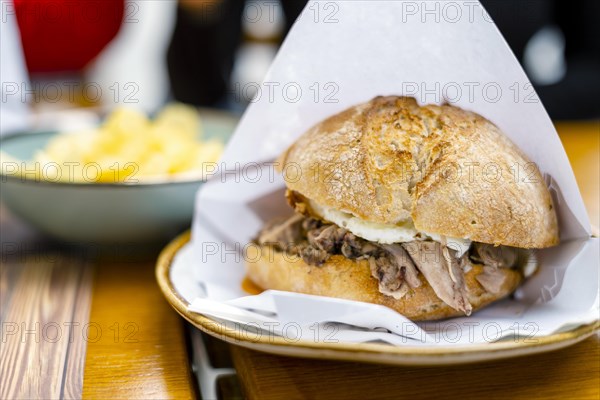 Delicious bun with delicate piglet and egg with chips aside