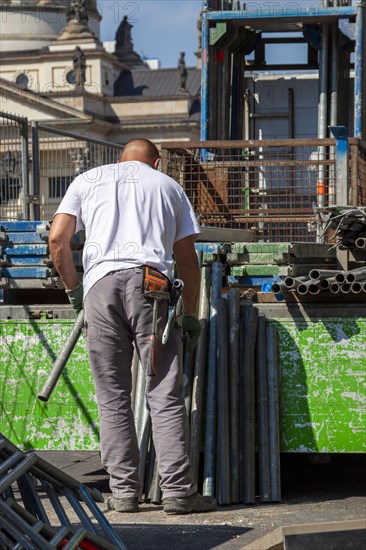 Construction worker loading a truck with scaffolding poles