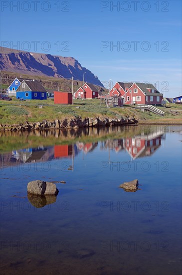 Wooden houses reflected in a body of water on a calm summer evening
