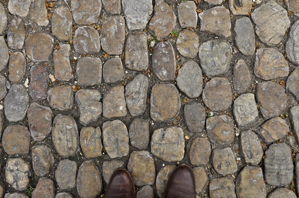 Brown shoe tips on brown stone pavement