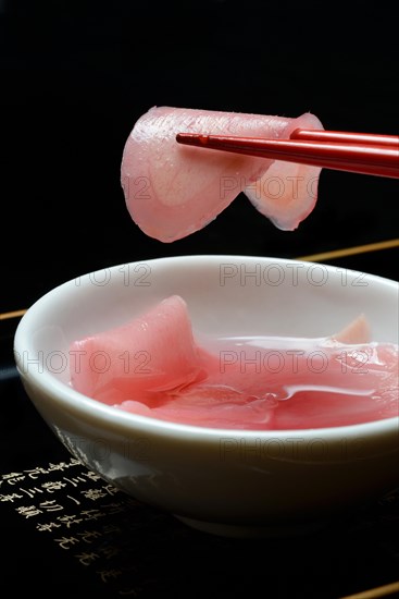 Sliced pickled ginger on chopsticks and in bowl