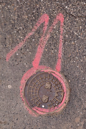 Manhole cover lid and number 11 in pink
