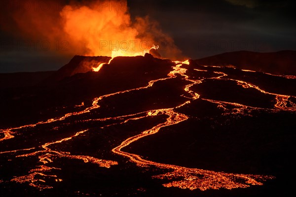 Lava spurting out of crater and reddish illuminated smoke cloud