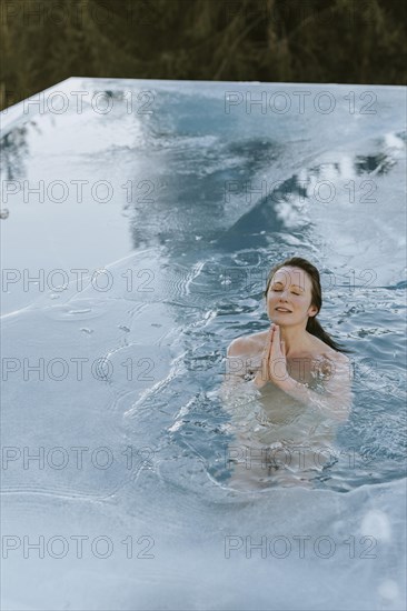 Woman folds her hands while ice bathing in the pool